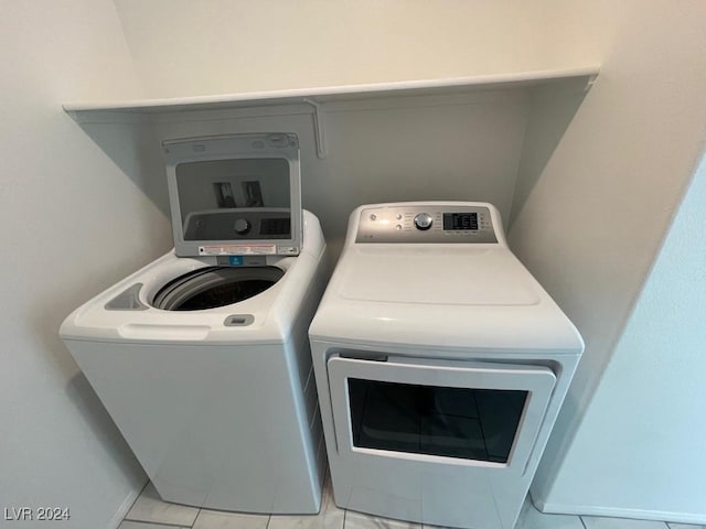 laundry room with washing machine and clothes dryer and light tile patterned flooring