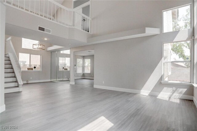 unfurnished living room with a wealth of natural light, wood-type flooring, and a high ceiling