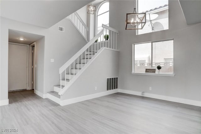 stairs with hardwood / wood-style floors, a high ceiling, and an inviting chandelier