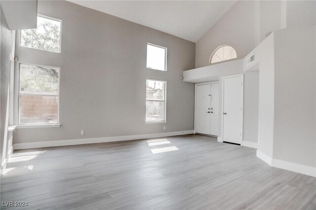 foyer entrance with light wood-type flooring, high vaulted ceiling, and a healthy amount of sunlight