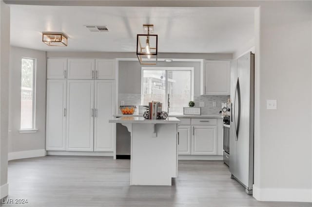 kitchen with backsplash, a breakfast bar, stainless steel appliances, white cabinets, and a kitchen island