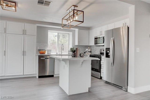 kitchen featuring stainless steel appliances, a kitchen island, and white cabinetry