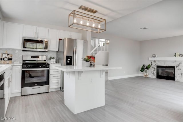 kitchen featuring decorative light fixtures, a kitchen bar, white cabinetry, and appliances with stainless steel finishes