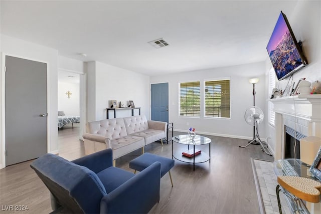 living room with hardwood / wood-style flooring and a tiled fireplace