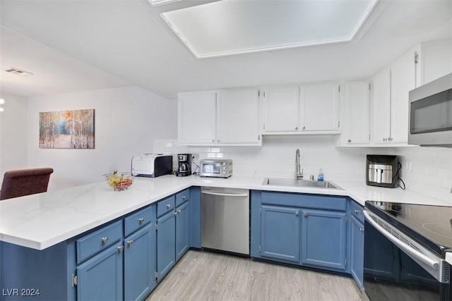 kitchen with kitchen peninsula, sink, stainless steel appliances, and blue cabinets