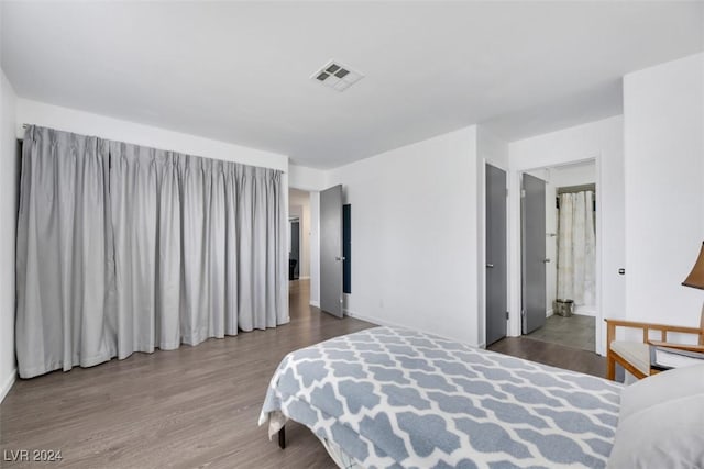 bedroom with ensuite bath and hardwood / wood-style floors