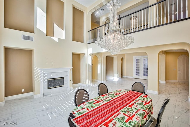 dining room featuring a high end fireplace, a high ceiling, and an inviting chandelier