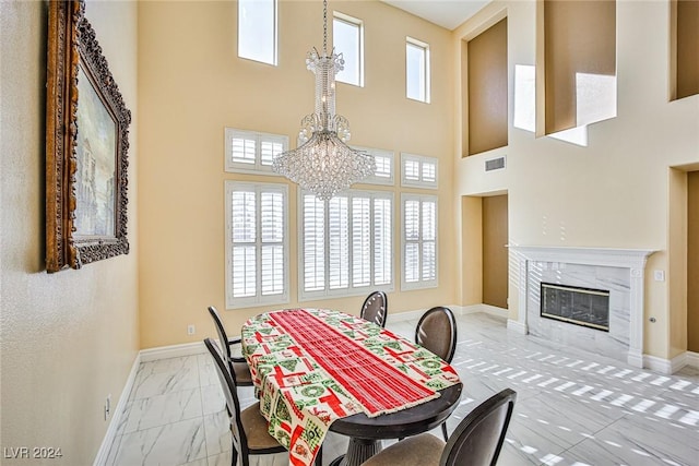 dining room featuring a high end fireplace, a chandelier, and a high ceiling