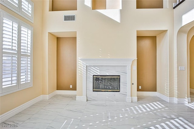 unfurnished living room featuring a towering ceiling and a premium fireplace