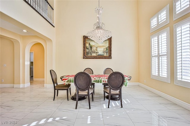 dining room featuring a towering ceiling and a notable chandelier