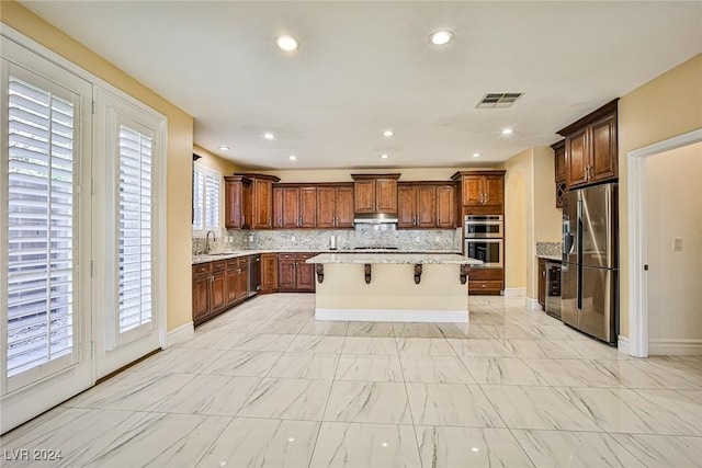 kitchen featuring sink, a breakfast bar area, decorative backsplash, a kitchen island, and stainless steel appliances