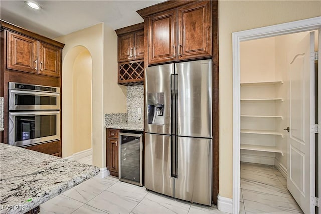 kitchen with backsplash, wine cooler, light stone counters, and stainless steel appliances