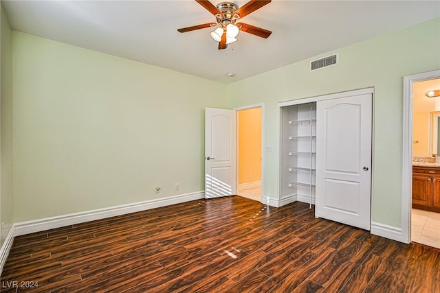 unfurnished bedroom with ceiling fan, dark hardwood / wood-style flooring, ensuite bathroom, and a closet