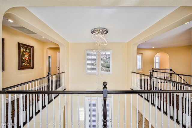 corridor with a healthy amount of sunlight and an inviting chandelier