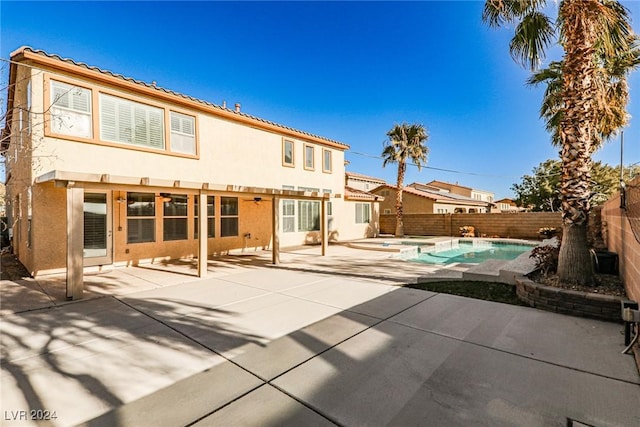 rear view of house featuring a fenced in pool and a patio area