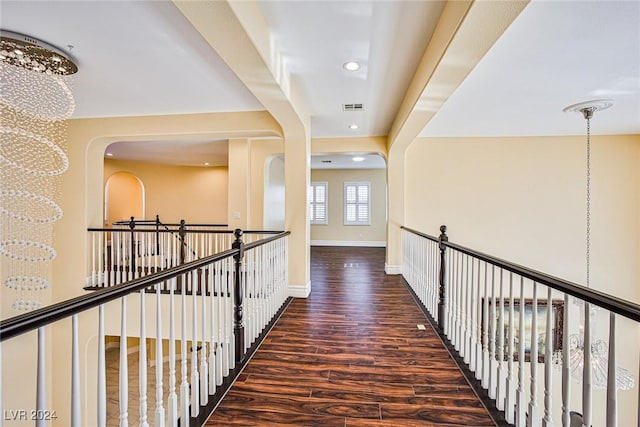 corridor with dark hardwood / wood-style floors and a notable chandelier