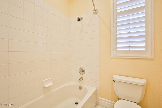 bathroom featuring a wealth of natural light, tiled shower / bath combo, and toilet