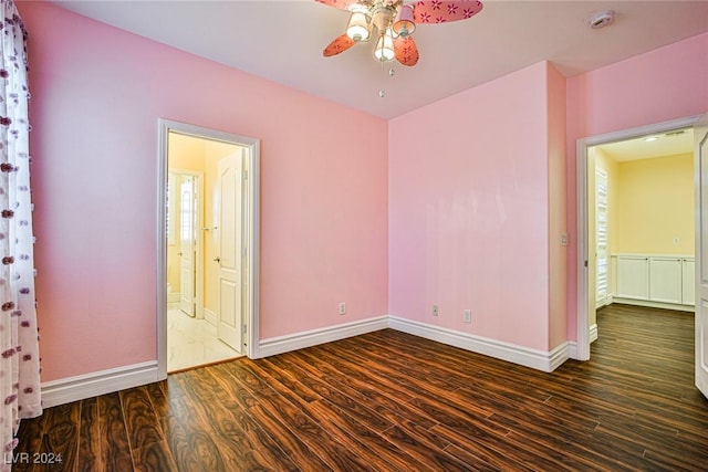 unfurnished bedroom with multiple windows, ceiling fan, ensuite bathroom, and dark hardwood / wood-style floors