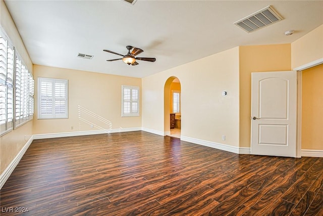 empty room featuring plenty of natural light, ceiling fan, and dark hardwood / wood-style flooring