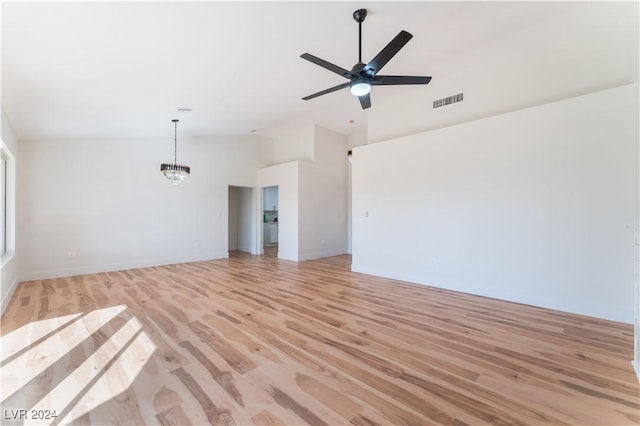 unfurnished living room featuring ceiling fan with notable chandelier, high vaulted ceiling, and light hardwood / wood-style flooring