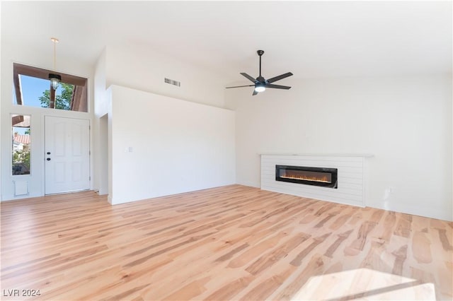 unfurnished living room featuring high vaulted ceiling, light hardwood / wood-style flooring, and ceiling fan