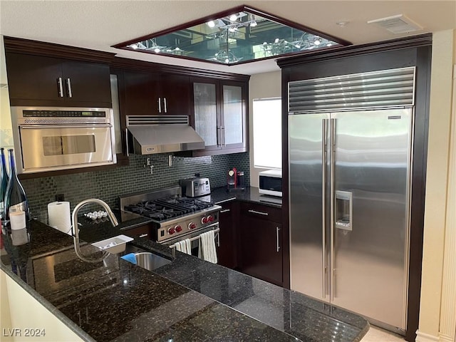 kitchen with decorative backsplash, dark brown cabinets, extractor fan, and high end appliances