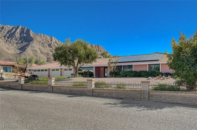 ranch-style house with solar panels, a mountain view, and a garage