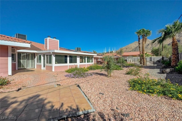 rear view of property with a mountain view, central AC, a patio area, and a sunroom