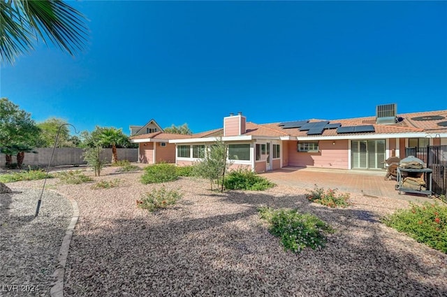 rear view of property featuring solar panels, a patio, and central AC