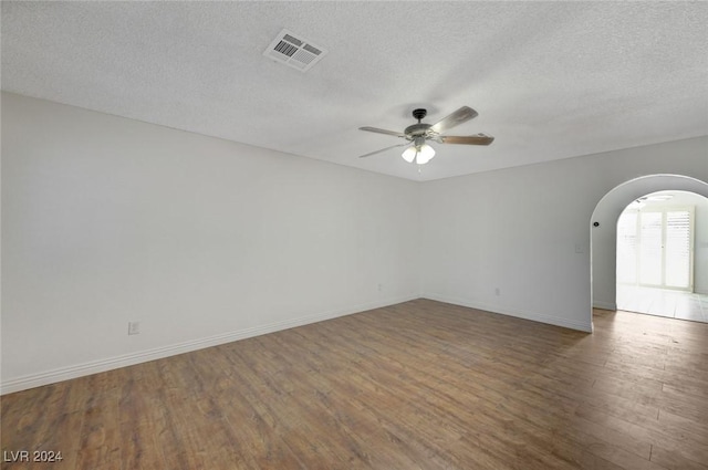 empty room with ceiling fan, dark wood-type flooring, and a textured ceiling