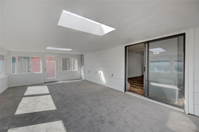 unfurnished living room featuring carpet floors and a skylight