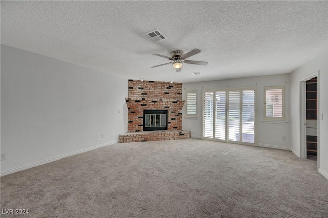 unfurnished living room featuring ceiling fan, a fireplace, light carpet, and a textured ceiling