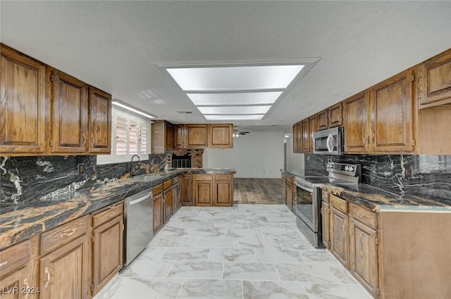 kitchen with a textured ceiling, sink, backsplash, and appliances with stainless steel finishes