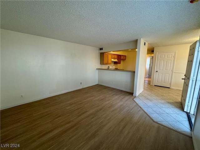 unfurnished living room with a textured ceiling and light hardwood / wood-style flooring