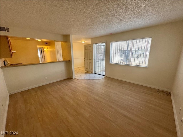 unfurnished living room featuring a textured ceiling and light wood-type flooring