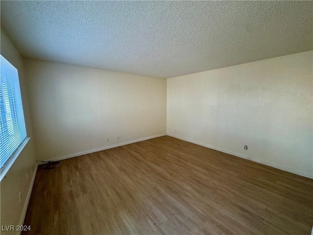 empty room with hardwood / wood-style floors and a textured ceiling