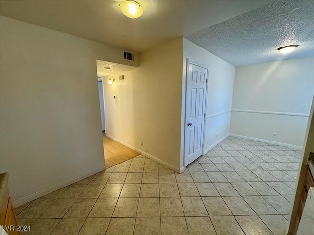 empty room with light tile patterned flooring and a textured ceiling