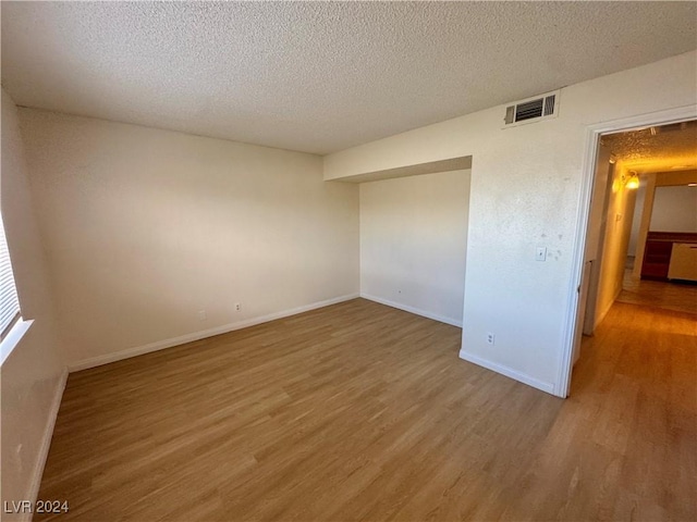 empty room featuring wood-type flooring and a textured ceiling