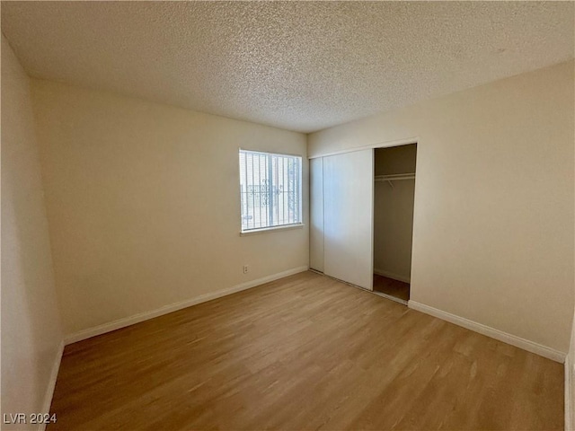 unfurnished bedroom with a closet, a textured ceiling, and light hardwood / wood-style flooring