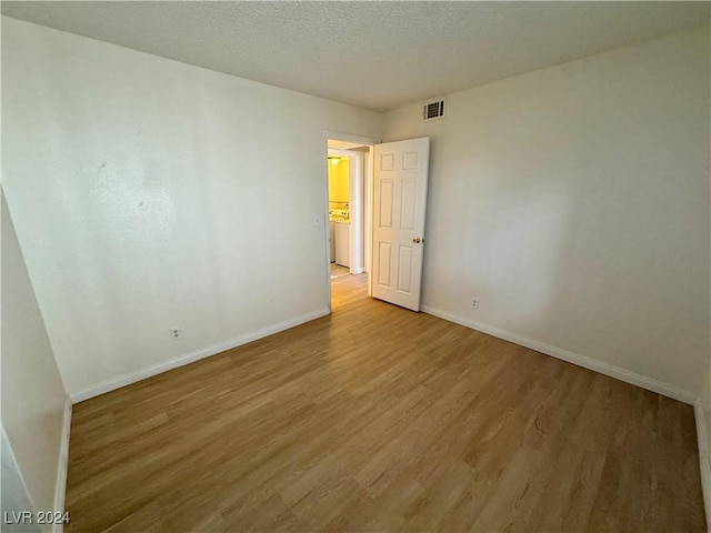 spare room featuring light wood-type flooring and a textured ceiling