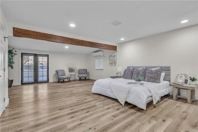 bedroom featuring french doors, light hardwood / wood-style flooring, and an AC wall unit