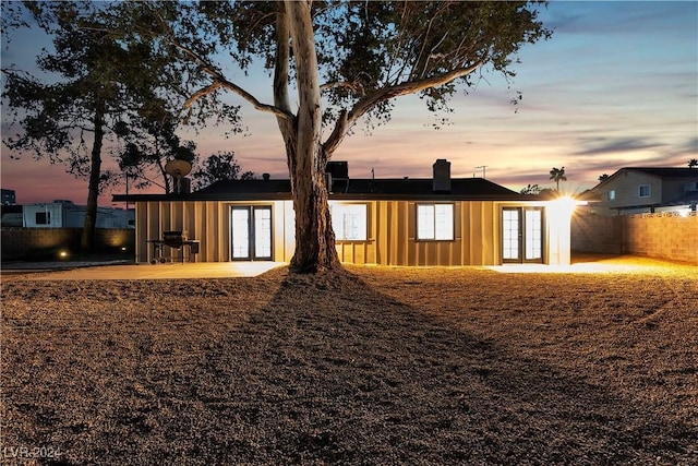 back house at dusk featuring a patio area and french doors