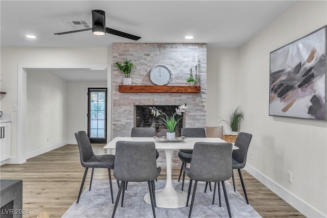 dining space featuring hardwood / wood-style flooring, ceiling fan, and a fireplace