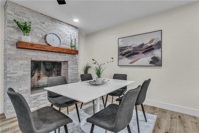 dining room featuring a stone fireplace and light hardwood / wood-style flooring