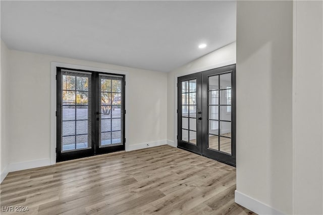 doorway with light hardwood / wood-style floors, vaulted ceiling, and french doors