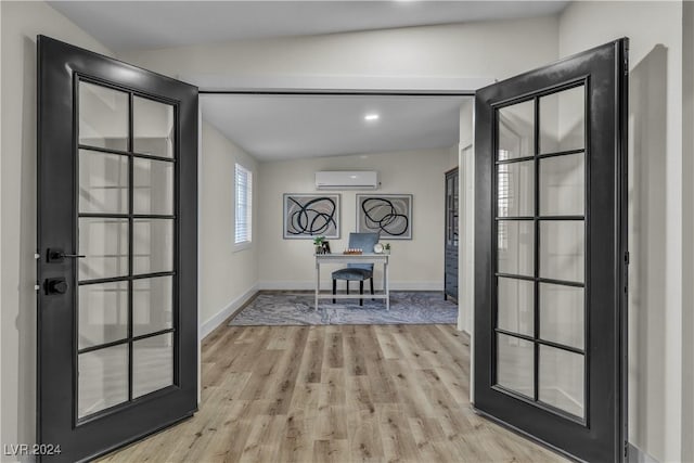 foyer featuring french doors, light hardwood / wood-style flooring, lofted ceiling, and a wall unit AC