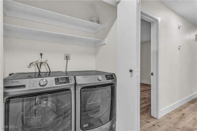 laundry area with washing machine and dryer and light wood-type flooring