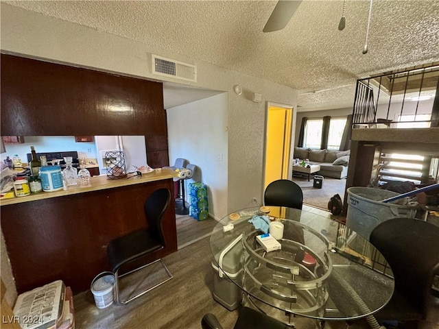 dining room with wood-type flooring, a textured ceiling, and ceiling fan