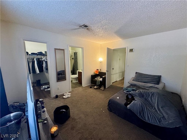 carpeted bedroom featuring a walk in closet, a textured ceiling, ensuite bath, and a closet