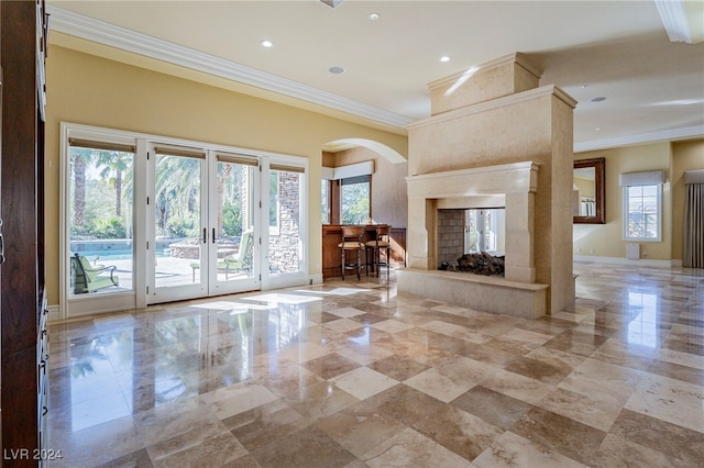 unfurnished living room with french doors, a high end fireplace, a healthy amount of sunlight, and ornamental molding